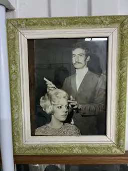 Retrato emoldurado de um profissional cortando cabelo